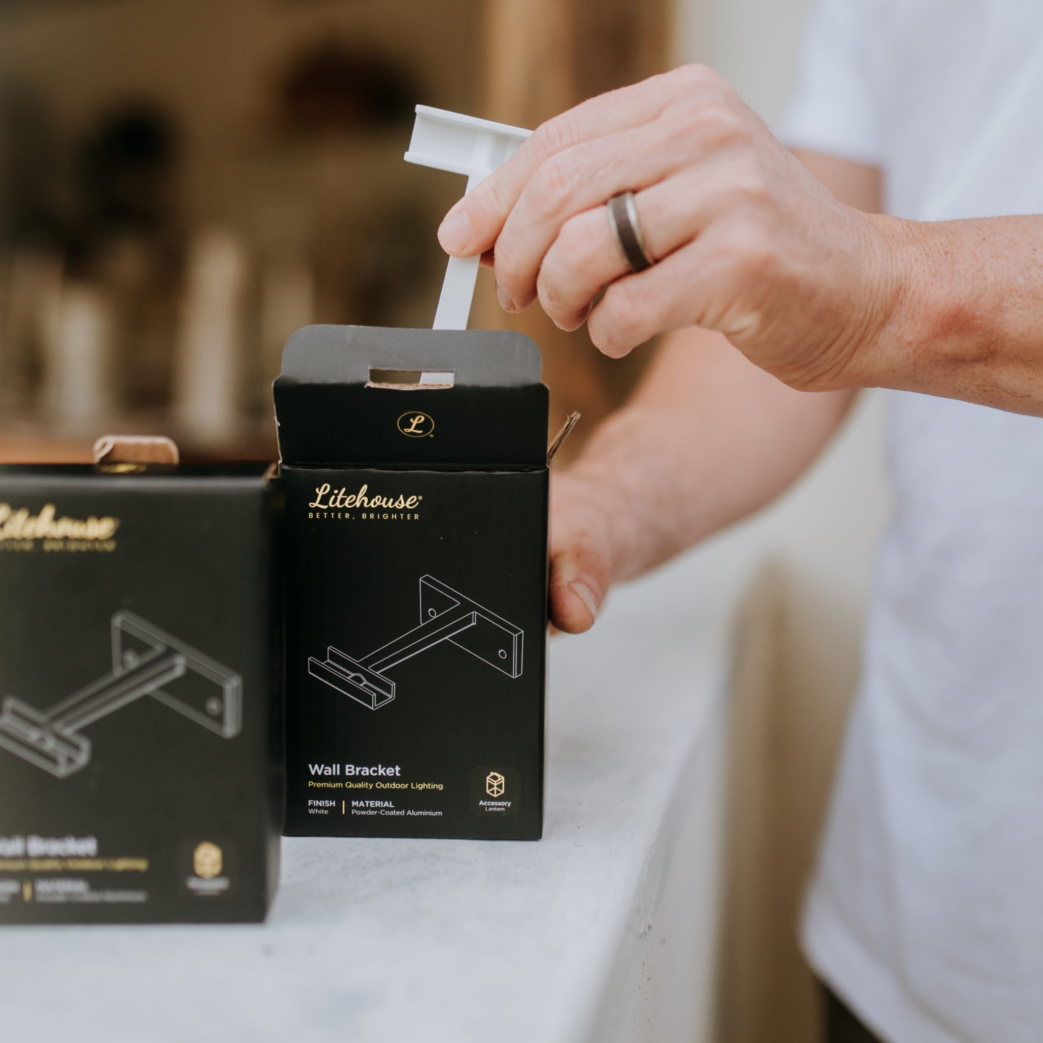 Person opening a Litehouse wall bracket packaging with a blurred background