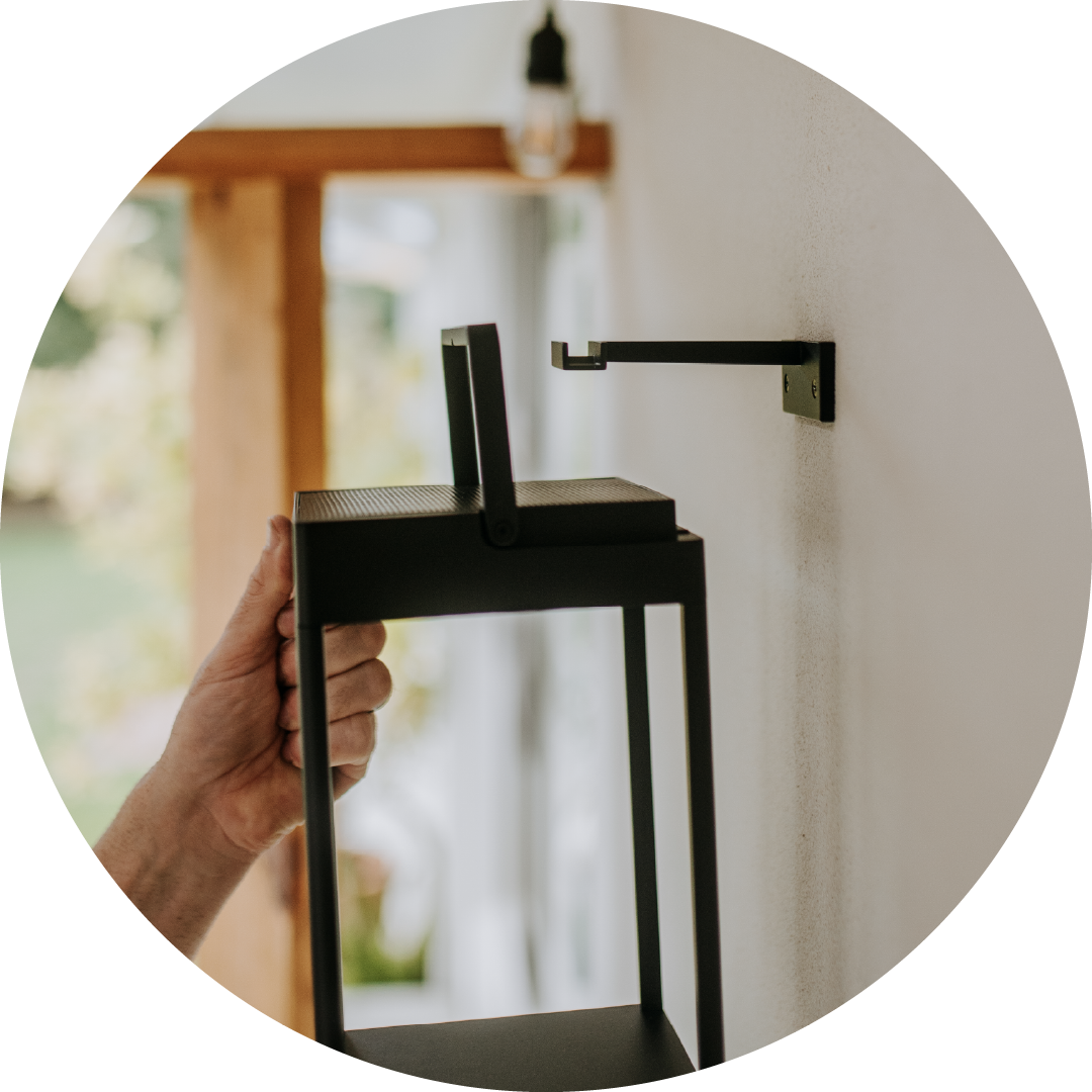 Person holding a modern black outdoor lamp with a blurred background